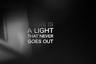 Inspirational quote 'There is a light that never goes out' on a black gradient background.