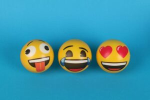 Three playful emoji balls with different expressions on a blue background.